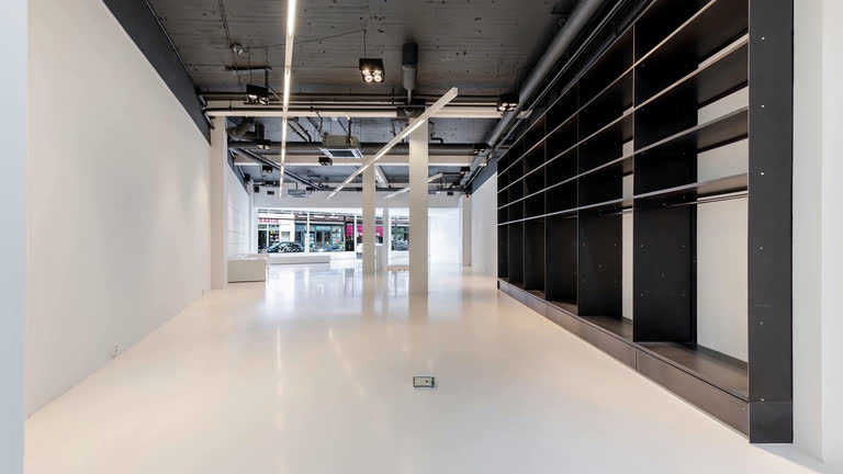 Empty white retail interior with dark shelving, photographed for the listing